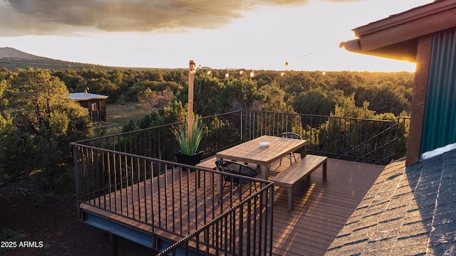 wooden terrace with a view of trees and outdoor dining space