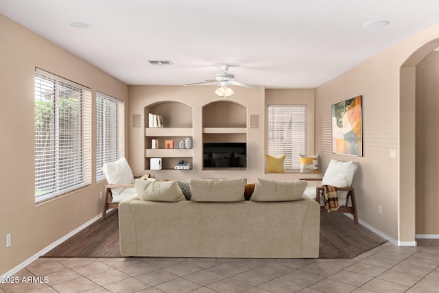 4426 E Coyote Wash Dr, Cave Creek, AZ 85331 - living room featuring light tile patterned floors, built in shelves, baseboards, arched walkways, and ceiling fan