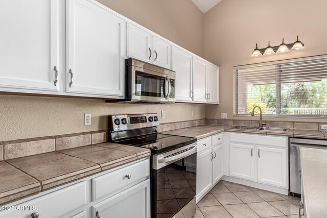 4426 E Coyote Wash Dr, Cave Creek, AZ 85331 - kitchen with appliances with stainless steel finishes, a sink, white cabinets, light tile patterned floors, and lofted ceiling