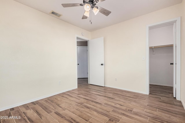 unfurnished bedroom with a walk in closet, light hardwood / wood-style flooring, a closet, and ceiling fan