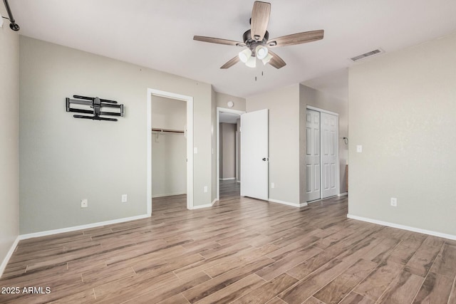 unfurnished bedroom with two closets, ceiling fan, and light hardwood / wood-style flooring