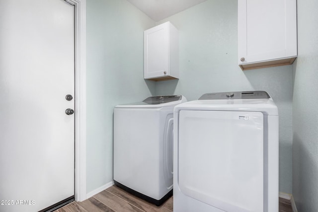 laundry room with cabinets, washer and clothes dryer, and light hardwood / wood-style flooring