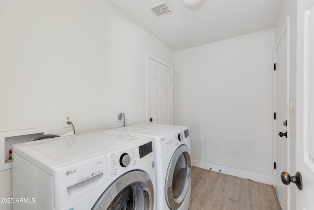 washroom with light wood finished floors, washing machine and clothes dryer, visible vents, laundry area, and baseboards