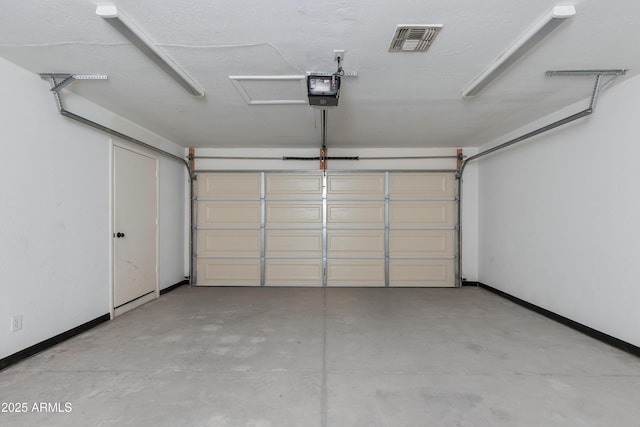 garage with a garage door opener, visible vents, and baseboards