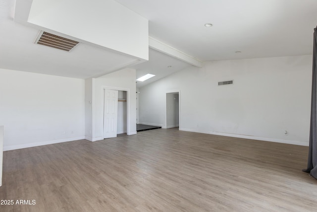 empty room featuring vaulted ceiling with beams, light wood finished floors, visible vents, and baseboards