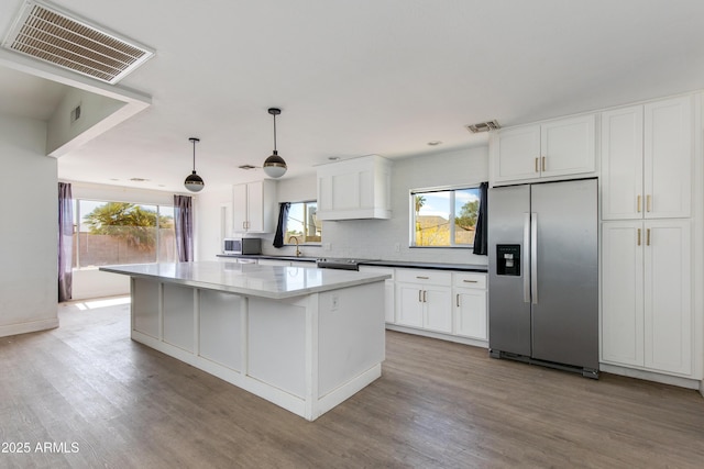 kitchen with visible vents, white cabinets, a kitchen island, light wood-type flooring, and stainless steel refrigerator with ice dispenser