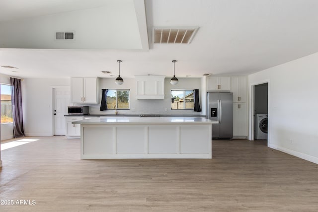 kitchen with visible vents, washer / clothes dryer, stainless steel appliances, and a center island