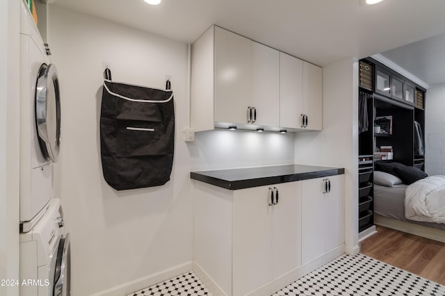 laundry area with cabinets, light hardwood / wood-style flooring, and stacked washer and clothes dryer