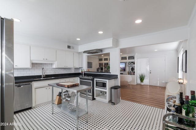 kitchen with crown molding, sink, light wood-type flooring, appliances with stainless steel finishes, and white cabinetry