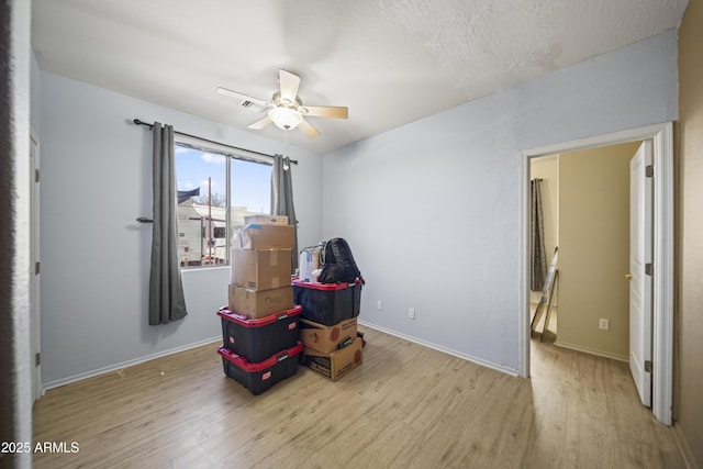 living area featuring visible vents, baseboards, wood finished floors, and a ceiling fan