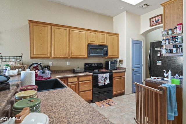 kitchen with visible vents, black appliances, a sink, arched walkways, and light tile patterned floors
