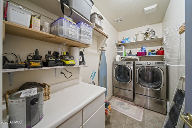 laundry room with washing machine and clothes dryer, visible vents, laundry area, tile patterned floors, and a textured ceiling