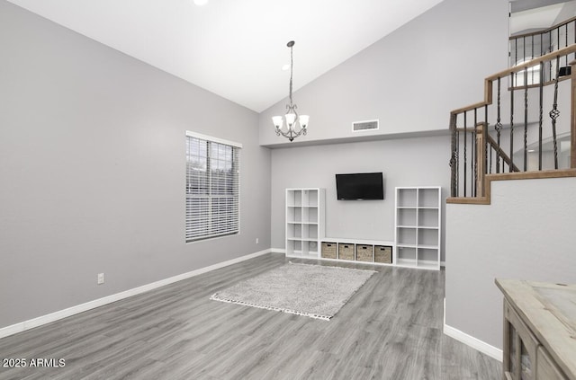 unfurnished living room with hardwood / wood-style flooring, high vaulted ceiling, and a chandelier