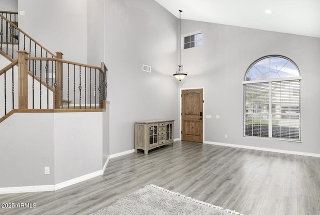 unfurnished living room featuring high vaulted ceiling and light wood-type flooring