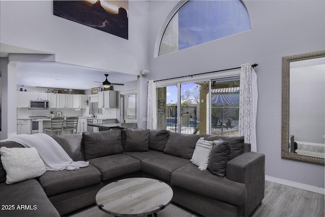 living room featuring a high ceiling, sink, and light wood-type flooring