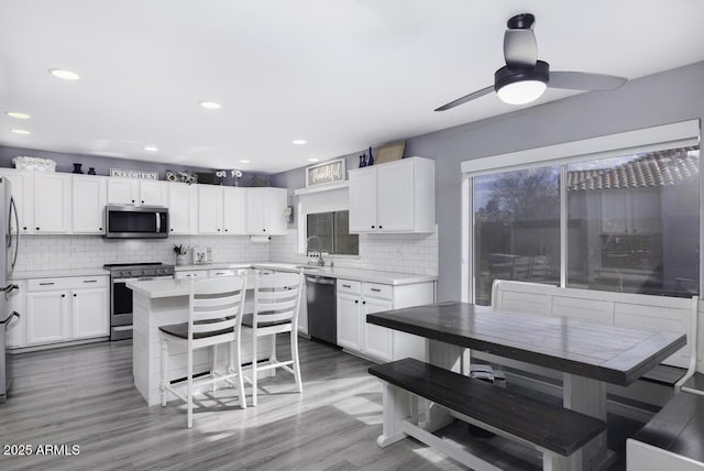 kitchen with white cabinetry, appliances with stainless steel finishes, a center island, and a kitchen bar