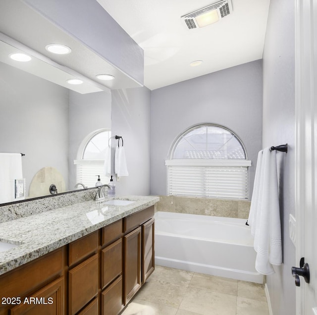 bathroom with tile patterned flooring, vanity, and a tub