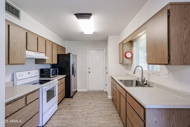 kitchen featuring appliances with stainless steel finishes, sink, light hardwood / wood-style flooring, and a textured ceiling