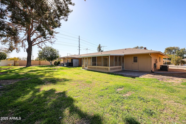 rear view of property with a yard, a patio area, a sunroom, and central air condition unit