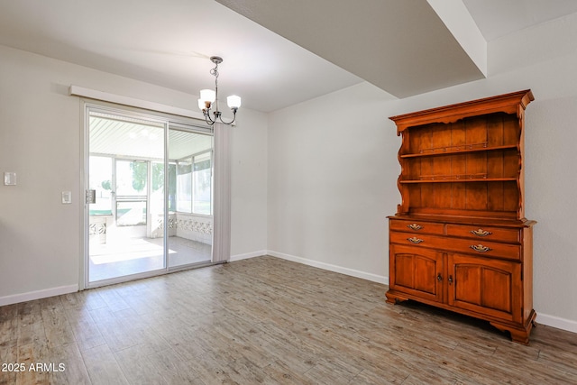 empty room with a chandelier and light hardwood / wood-style floors