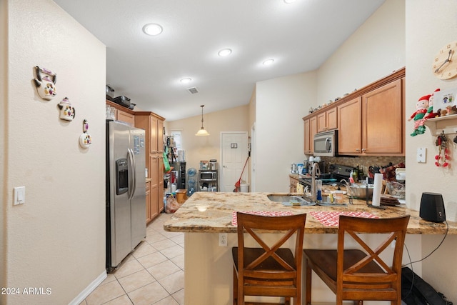 kitchen featuring a kitchen breakfast bar, kitchen peninsula, vaulted ceiling, light tile patterned floors, and appliances with stainless steel finishes