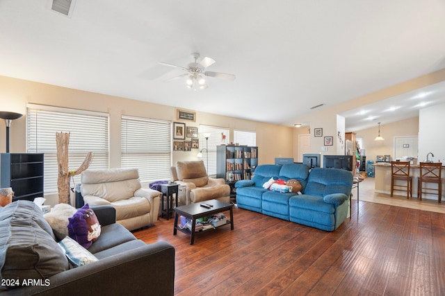 living area with lofted ceiling, ceiling fan, visible vents, and dark wood finished floors