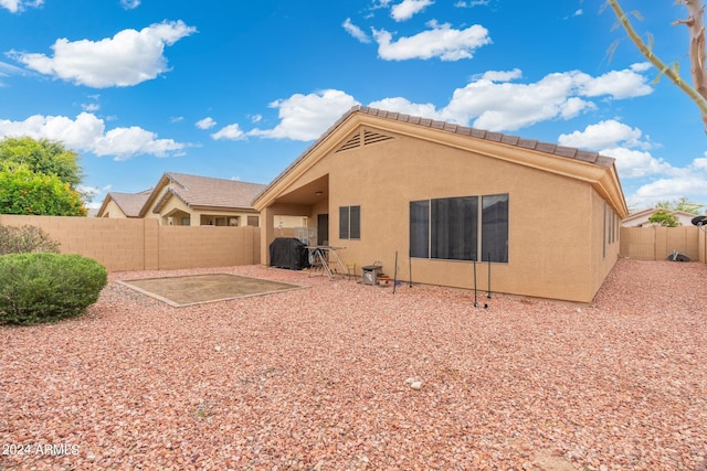 rear view of house featuring a fenced backyard, a patio, and stucco siding