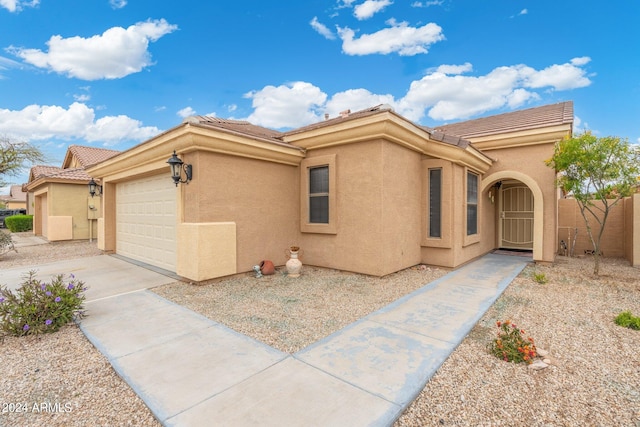 view of front of house with an attached garage, a tiled roof, concrete driveway, and stucco siding