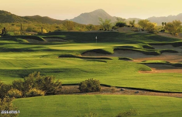 view of home's community with a yard, view of golf course, and a mountain view