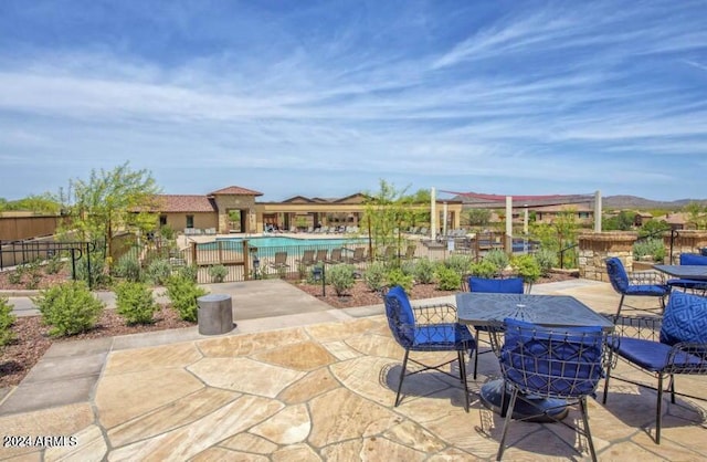 view of patio featuring outdoor dining space, fence, and a community pool