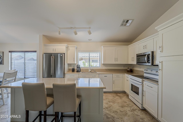 16523 W Desert Bloom St, Goodyear, AZ 85338 - kitchen featuring appliances with stainless steel finishes, a breakfast bar, white cabinets, and a center island