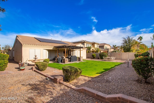 rear view of property with a patio area, an outdoor living space, a yard, and solar panels