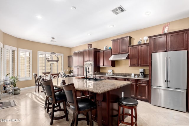 kitchen featuring sink, hanging light fixtures, an island with sink, a breakfast bar area, and appliances with stainless steel finishes