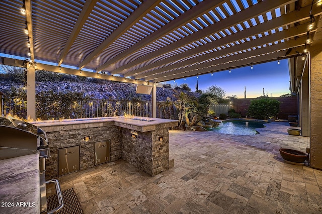 patio terrace at dusk with pool water feature, a fenced in pool, a pergola, and exterior kitchen