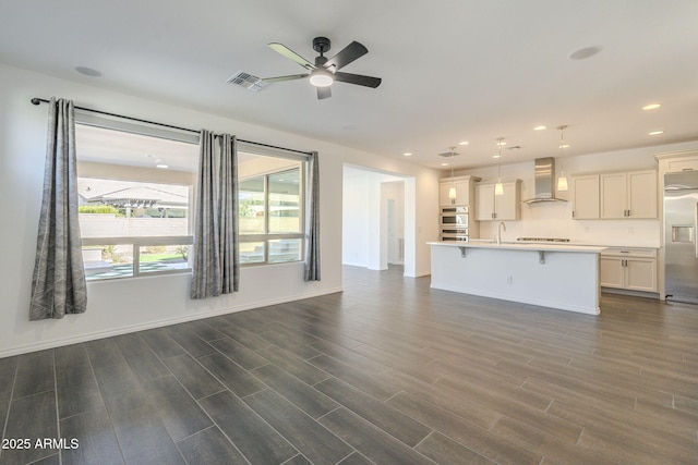 unfurnished living room featuring ceiling fan and sink