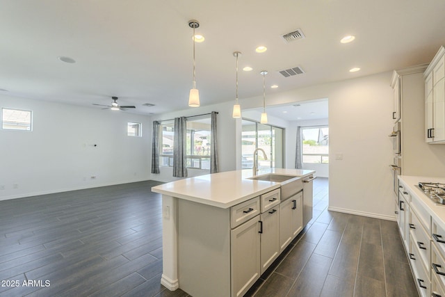 kitchen with white cabinetry, a kitchen island with sink, sink, decorative light fixtures, and ceiling fan