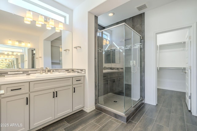 bathroom with vanity, backsplash, and a shower with door