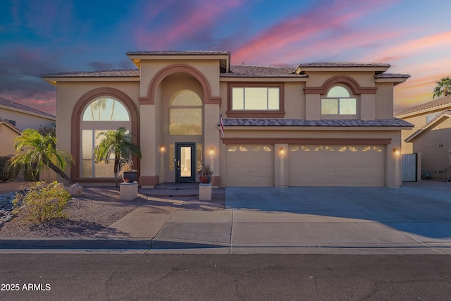 mediterranean / spanish-style house with a garage, driveway, and stucco siding