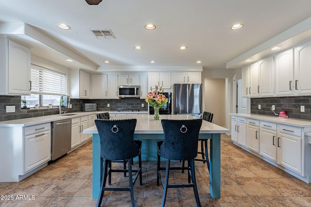 12925 W Llano Dr, Litchfield Park, AZ 85340 - kitchen featuring a center island, a breakfast bar area, visible vents, appliances with stainless steel finishes, and white cabinetry