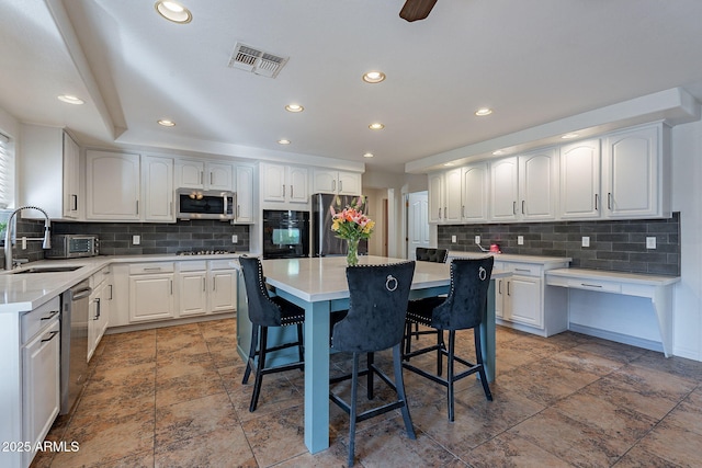 12925 W Llano Dr, Litchfield Park, AZ 85340 - kitchen featuring appliances with stainless steel finishes, white cabinetry, a kitchen island, a sink, and a kitchen bar