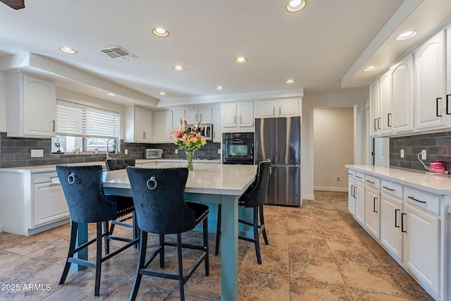 12925 W Llano Dr, Litchfield Park, AZ 85340 - kitchen featuring appliances with stainless steel finishes, a kitchen bar, white cabinetry, and a center island