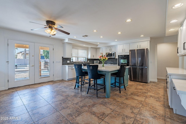 12925 W Llano Dr, Litchfield Park, AZ 85340 - kitchen featuring stainless steel appliances, a kitchen island, white cabinets, backsplash, and a kitchen bar