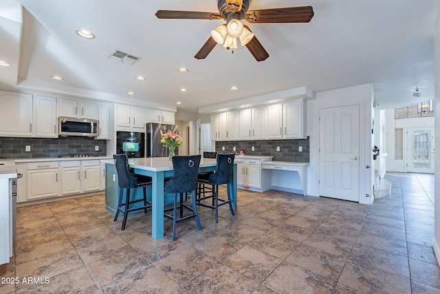12925 W Llano Dr, Litchfield Park, AZ 85340 - kitchen featuring white cabinets, a kitchen island, appliances with stainless steel finishes, and a breakfast bar