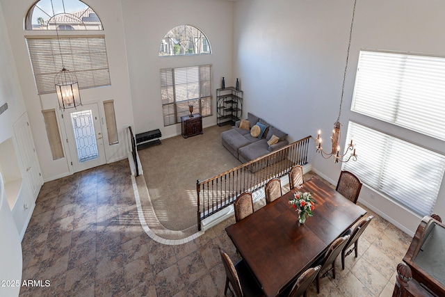 12925 W Llano Dr, Litchfield Park, AZ 85340 - dining area featuring carpet floors, a notable chandelier, a towering ceiling, and baseboards