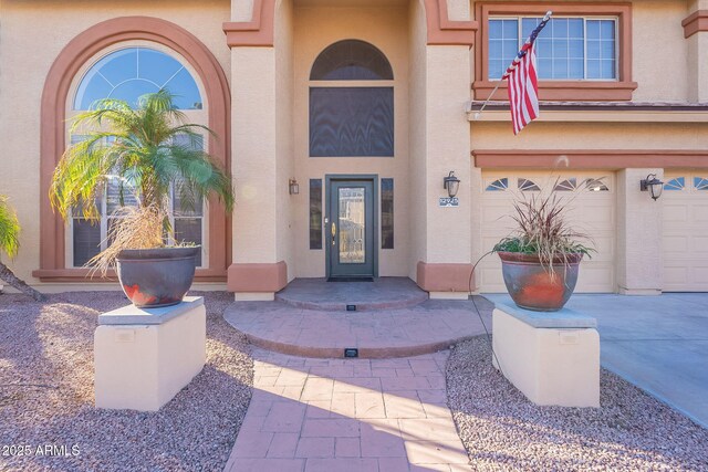 12925 W Llano Dr, Litchfield Park, AZ 85340 - view of exterior entry with driveway, an attached garage, and stucco siding