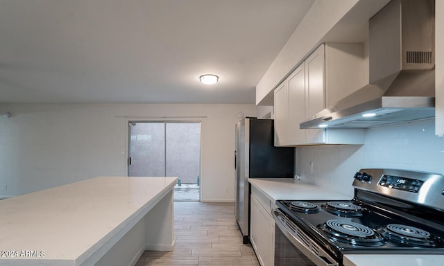 kitchen with wall chimney exhaust hood, white cabinetry, appliances with stainless steel finishes, light wood-type flooring, and decorative backsplash