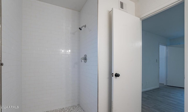 bathroom with hardwood / wood-style flooring and tiled shower