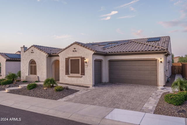 mediterranean / spanish-style house with solar panels and a garage