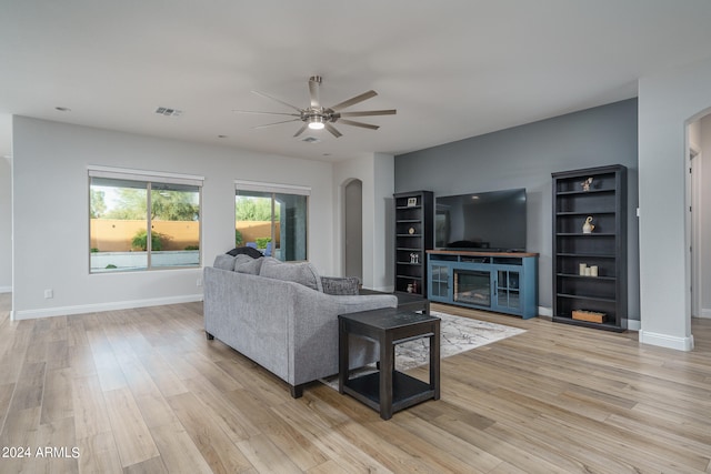 living room with a fireplace, light wood-type flooring, and ceiling fan