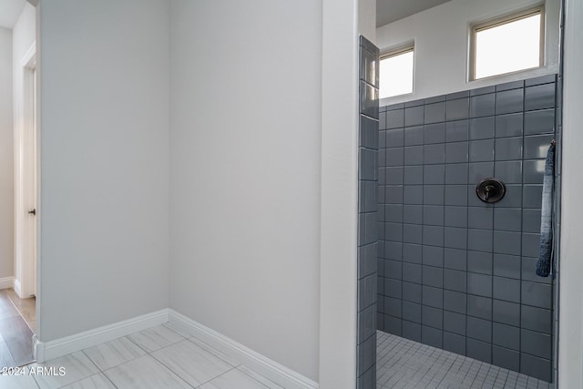 bathroom featuring tiled shower and tile patterned flooring